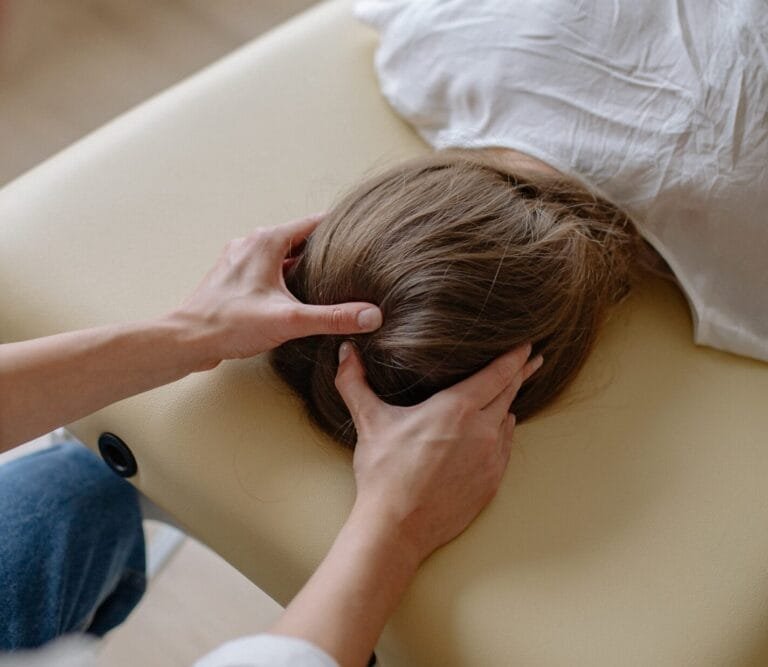 masseuse massant le crane d'une personne habillée