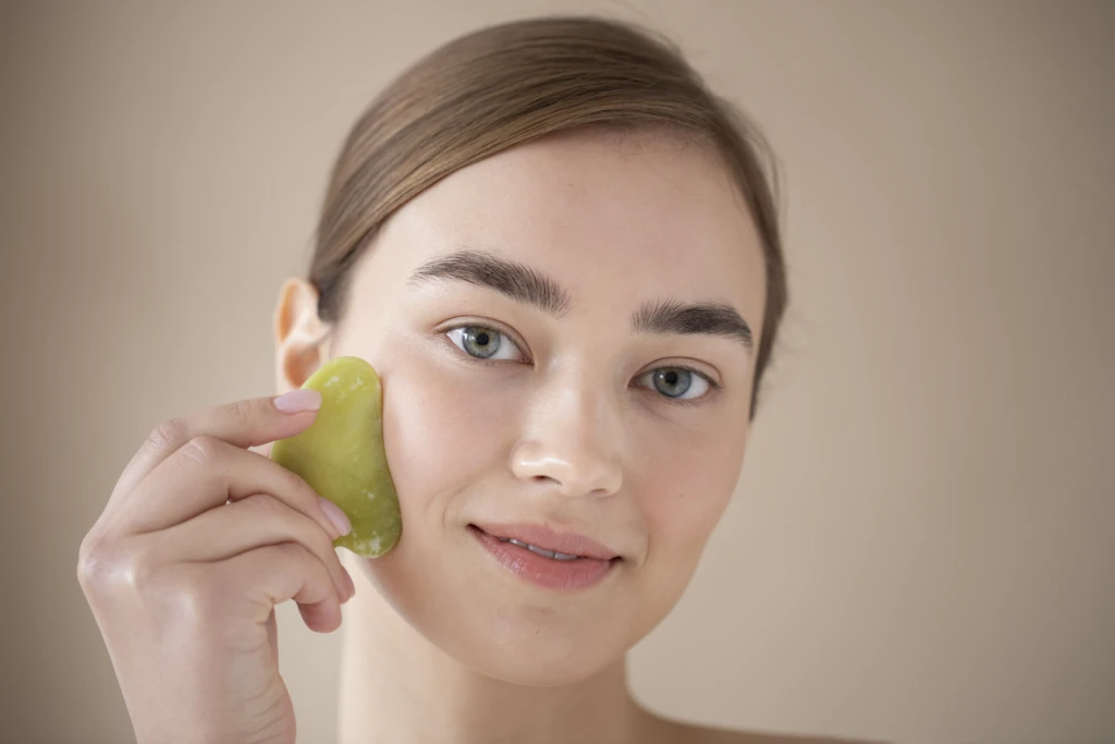 portrait beautiful woman with clear skin using guasha massage her face